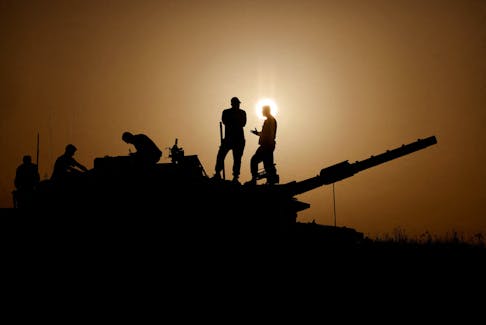 Israeli soldiers stand on a tank, amid the ongoing conflict between Israel and the Palestinian group Hamas, near Israel's border with Gaza in southern Israel, November 23, 2023.