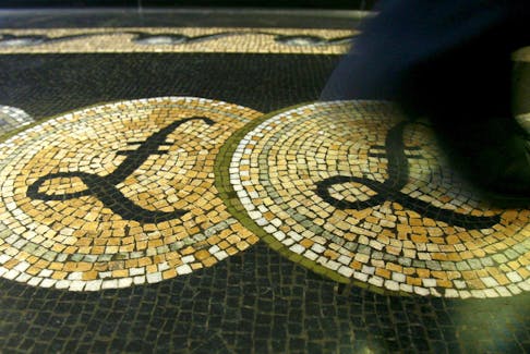 An employee is seen walking over a mosaic of pound sterling symbols set in the floor of the front hall of the Bank of England in London, in this March 25, 2008 file photograph.