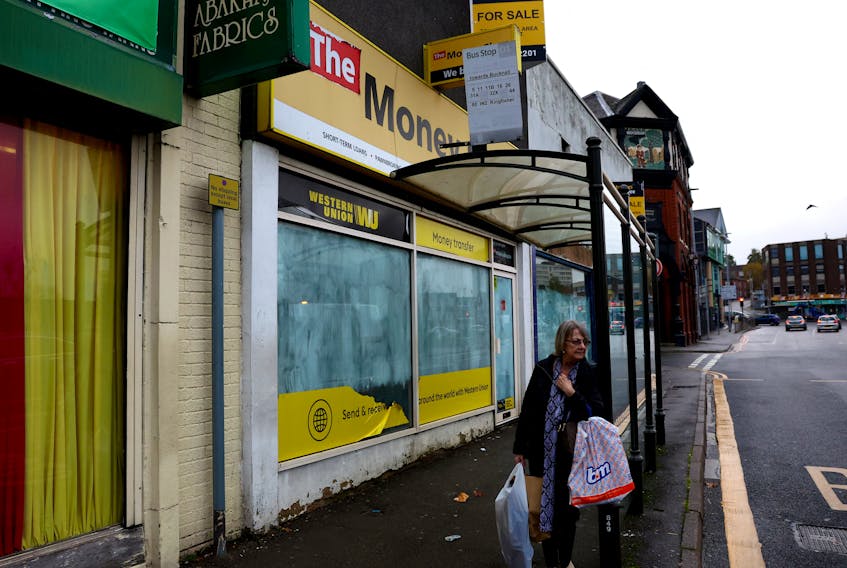 A woman with shopping bags waits for a bus, Hanley, Britain, November 20, 2023.