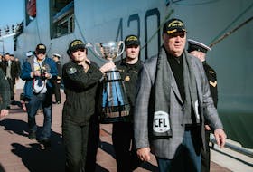 CFL Commissioner Randy Ambrosie and two members of HMCS Harry DeWolf's crew carrying the Grey Cup. The Halifax-based warship saw a COVID outbreak after almost half the crew attended the game in Hamilton.