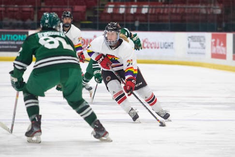 UNB’s Reagan Minor, 27, moves the puck forward as the UPEI Panthers’ Elizabeth Beiersdorfer, 92, defends. The Reds won their Pride game 2-1 in a shootout at the Aitken Centre in Fredericton. James West/UNB Athletics