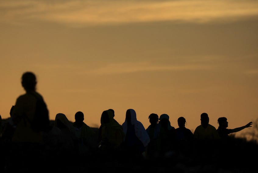 File photo: Migrants are seen in silhouette, as they board a ship to be transferred to the mainland, on the Sicilian island of Lampedusa, Italy, September 15, 2023.