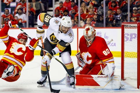 Calgary Flames defenceman Dennis Gilbert collides with Vegas Golden Knights forward William Carrier in front of Flames goaltender Dan Vladar at the Scotiabank Saddledome in Calgary on Monday, Nov. 27, 2023.