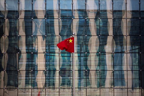 A Chinese national flag flutters at the headquarters of a commercial bank on a financial street near the headquarters of the People's Bank of China, China's central bank, in central Beijing November 24, 2014.