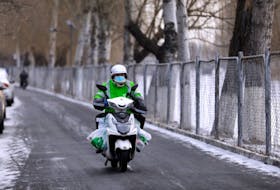 A Meituan delivery worker rides a scooter carrying vegetables on a snowy day in Beijing, China January 19, 2021.