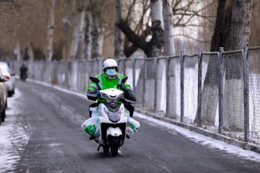 A Meituan delivery worker rides a scooter carrying vegetables on a snowy day in Beijing, China January 19, 2021.