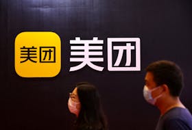 People walk past the logo of Chinese food delivery firm Meituan at its booth at the 2022 World Robot Conference in Beijing, China, Aug. 18, 2022.