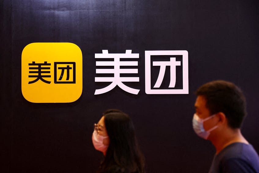 People walk past the logo of Chinese food delivery firm Meituan at its booth at the 2022 World Robot Conference in Beijing, China, Aug. 18, 2022.