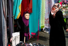 A woman walks past a mannequin wearing an hijab headscarf at a market in the Brussels district of Molenbeek, Belgium, August 14, 2016. 