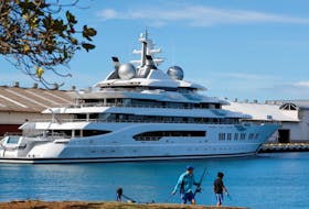 Fishermen set up their gear across the harbour from the Russian-owned super yacht Amadea, seized in Fiji by American law enforcement, in Honolulu, Hawaii, U.S. June 17, 2022.