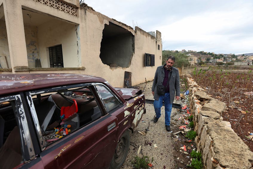 Chaker Hijazi walks past a vehicle and a house that were damaged during Israeli shelling in recent weeks, prior to a truce taking hold between Hamas and Israel, that has informally extended to southern Lebanon, in Meiss al-Jabal village, near the border with Israel, southern Lebanon November 28, 2023.