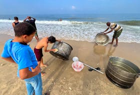Palestinians wash cooking pots with seawater, amid a lack of of clean water, as the conflict between Hamas and Israel continues, in Deir al-Balah, on a beach in the central Gaza Strip November 2, 2023.
