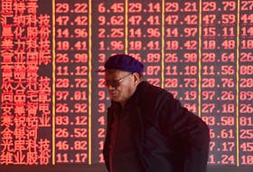 A man stands in front of an electronic board displaying stock information at a brokerage firm in Hangzhou, Zhejiang province, China April 1, 2019. Picture taken April 1, 2019.