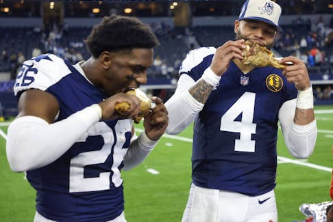 Dallas Cowboys cornerback DaRon Bland, left, and quarterback Dak Prescott celebrate by eating Thanksgiving turkey legs.