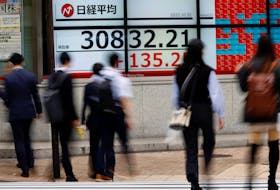 Pedestrians walk past an electronic board displaying Nikkei share average, outside a brokerage in Tokyo, Japan, October 31, 2023.