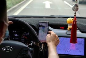 A driver of Chinese ride-hailing service Didi drives with a phone showing a navigation map on Didi's app, in Beijing, China July 5, 2021.