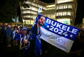 A man holds a campaign flag of El Salvador's President Nayib Bukele as he waits for the opening of the new building of El Salvador National Library, financed by China, in San Salvador, El Salvador November 14, 2023.