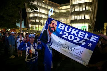 A man holds a campaign flag of El Salvador's President Nayib Bukele as he waits for the opening of the new building of El Salvador National Library, financed by China, in San Salvador, El Salvador November 14, 2023.