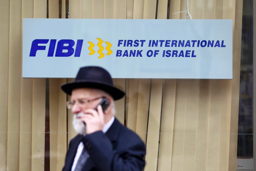 A man speaks on his mobile phone as he walks in front of a First International Bank of Israel branch in Jerusalem January 27, 2014.