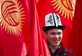 A man wearing a Kyrgyz national hat poses with national flags before a rally marking the Day of Flag and the Day of Kolpak in Bishkek, Kyrgyzstan March 4, 2013.  