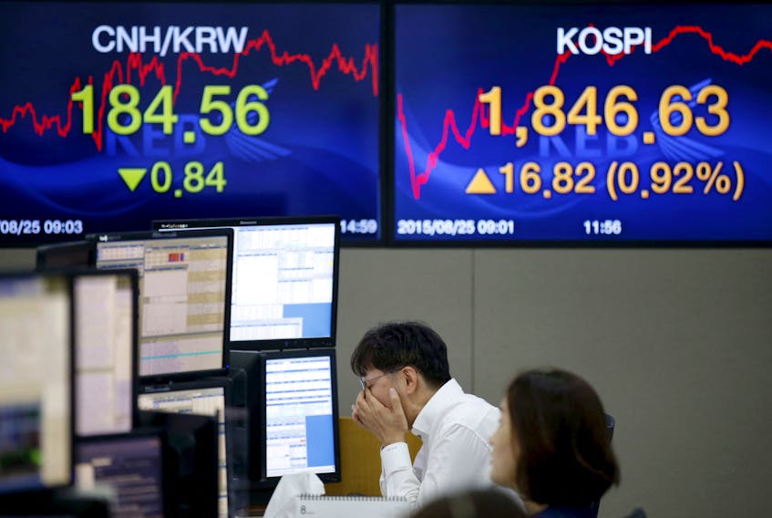 A currency dealer works in front of electronic boards showing the Korea Composite Stock Price Index (KOSPI) (R), and the exchange rates between the Chinese yuan and South Korean won (L), at a dealing room of a bank in Seoul, South Korea, August 25, 2015. 