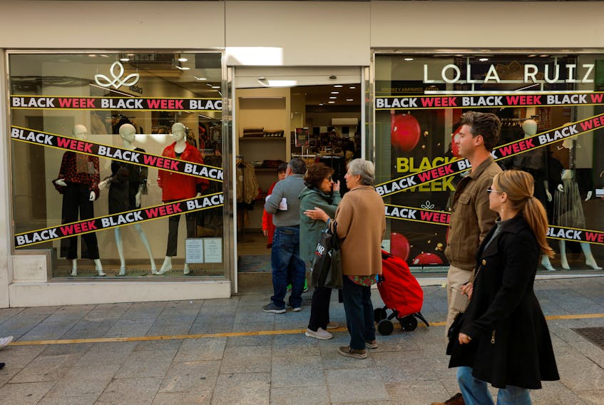 People walk past a shop displaying Black Friday sales signs, during Black Friday in Ronda, Spain November 24, 2023.