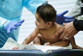 A doctor performs a routine checkup with a baby at his pediatric practice in Oyster Bay, New York, U.S., April 13, 2020. 