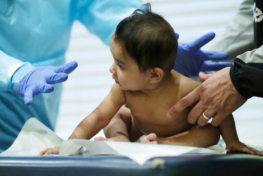 A doctor performs a routine checkup with a baby at his pediatric practice in Oyster Bay, New York, U.S., April 13, 2020. 