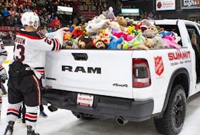 Members of the UNB Reds collect stuffed animals from the ice of the Aitken Centre Nov. 24, 2023, during a game against the UPEI Panthers men's hockey team as part of the New Brunswick team's annual Teddy Bear Toss night. Panthers also joined in gathering the plush toys from the ice.