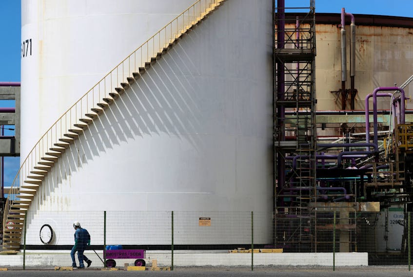 Workers pass in front of a tank at a chlorine-soda plant of the petrochemical company Braskem in Maceio, Brazil January 30, 2020. Picture taken January 30, 2020.