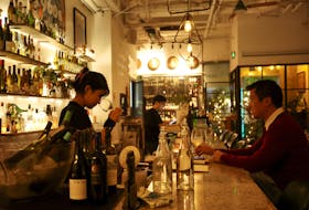 A staff member sniffs wine in a glass while a customer watches at  theTrio Wine Bar in Beijing, China November 1, 2023.