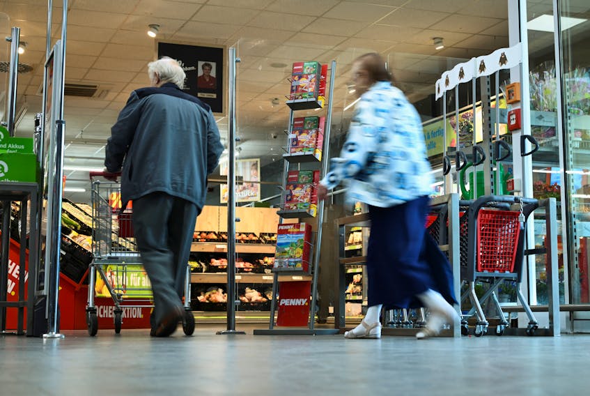 People walk by a flyer stand with a reference to the Europe-wide "true costs" campaign week by the discount supermarket Penny, in which nine selected products are given the calculated "real price" as the sales price, under consideration of the environmental costs, in Berlin, Germany August 1, 2023.