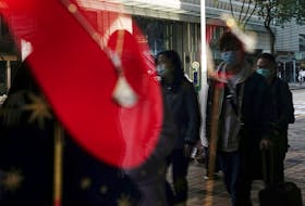 Shoppers walking past a luxury store are seen reflected in a shop window at Tsim Sha Tsui district in Hong Kong, China February 15, 2023.