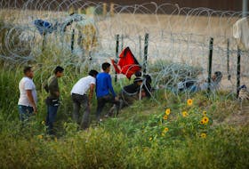 Migrants, seeking asylum in the United States, try to cross a razor wire fence deployed to inhibit the crossing of migrants into the United States, on the banks of the Rio Bravo River the border between the U.S. and Mexico, as seen from Ciudad Juarez, Mexico September 25, 2023.