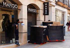 A delivery worker waits for the opening of a store of Spanish fashion chain Mango to deliver boxes with clothes, in Ronda, Spain, March 30, 2023.