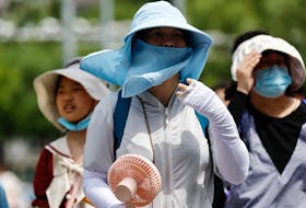 People wearing sun protection gear amid a heatwave walk on a street in Beijing, China July 1, 2023.