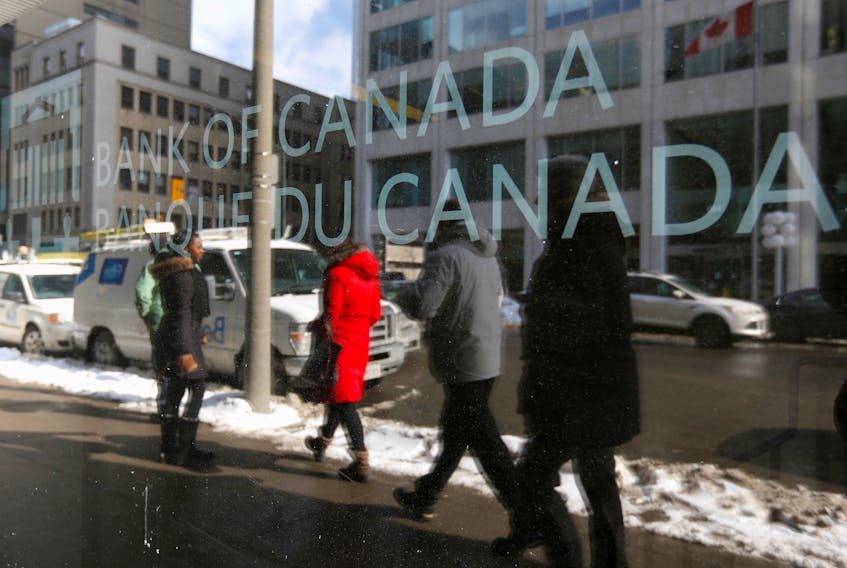 Pedestrians are reflected in a window while walking past the Bank of Canada office in Ottawa March 4, 2015.