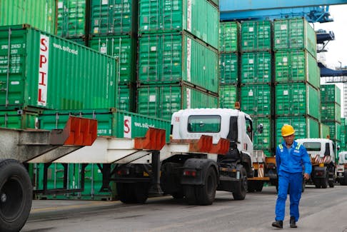 A worker walks past stacks of containers at Tanjung Priok port in Jakarta, Indonesia, February 3, 2023.