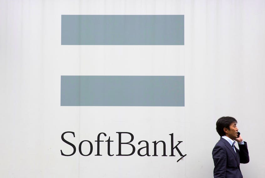 A man talks on the phone as he stand in front of an advertising poster of the SoftBank telecommunications company in Tokyo October 16, 2015.