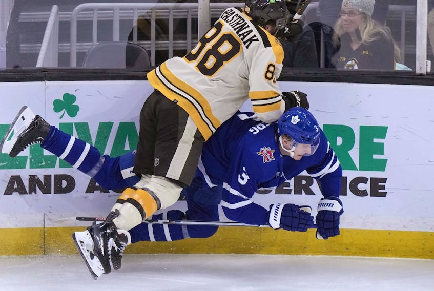 Boston Bruins winger David Pastrnak and Toronto Maple Leafs defenceman John Klingberg slam into the boards.