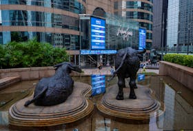 Bull statues are placed in font of screens showing the Hang Seng stock index and stock prices outside Exchange Square, in Hong Kong, China, August 18, 2023.