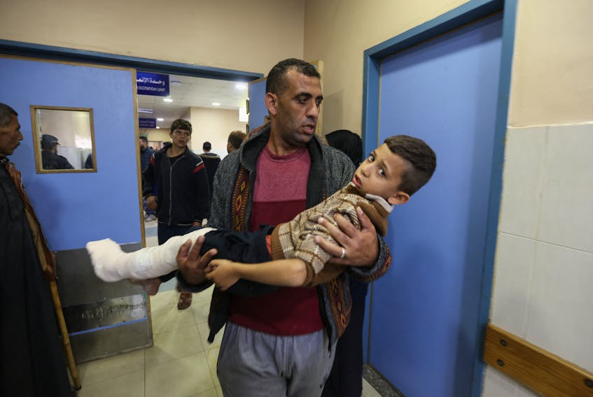 A Palestinian boy wounded in an Israeli strike is carried, after a temporary truce between Hamas and Israel expired, at Nasser hospital in Khan Younis in the southern Gaza Strip, December 1, 2023.