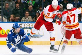Nikita Zadorov, centre, of the Calgary Flames checks Tyler Bertuzzi, left, of the Toronto Maple Leafs during the third period at Scotiabank Arena on Nov. 10, 2023 in Toronto.