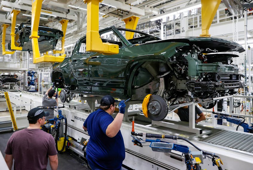 Employees works on an assembly line at startup Rivian Automotive's electric vehicle factory in Normal, Illinois, U.S. April 11, 2022. Picture taken April 11, 2022. 