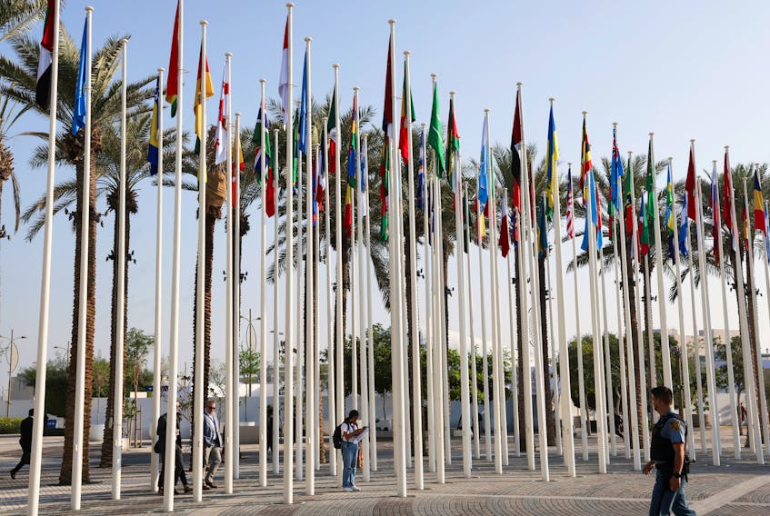 U.N. security officer walks near the flags at Dubai's Expo City during the United Nations Climate Change Conference (COP28) in Dubai, United Arab Emirates, December 10, 2023.