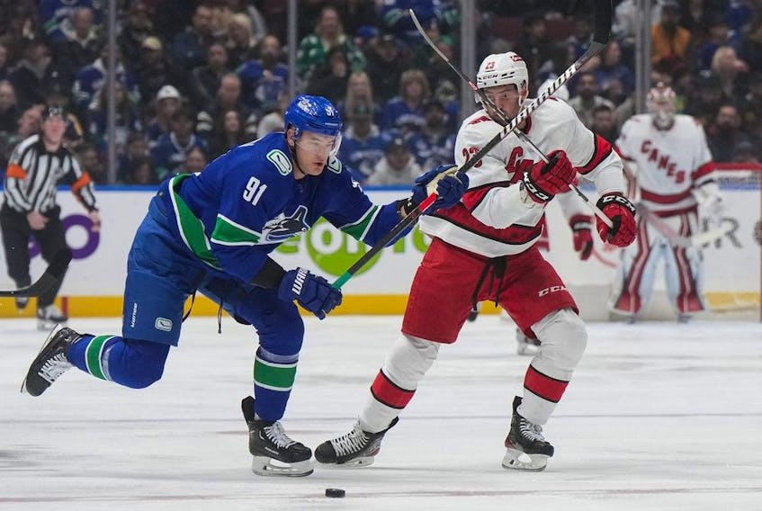 Vancouver Canucks' Nikita Zadorov, left, and Carolina Hurricanes' Stefan Noesen vie for the puck during the first period of an NHL hockey game in Vancouver, on Saturday, December 9, 2023.