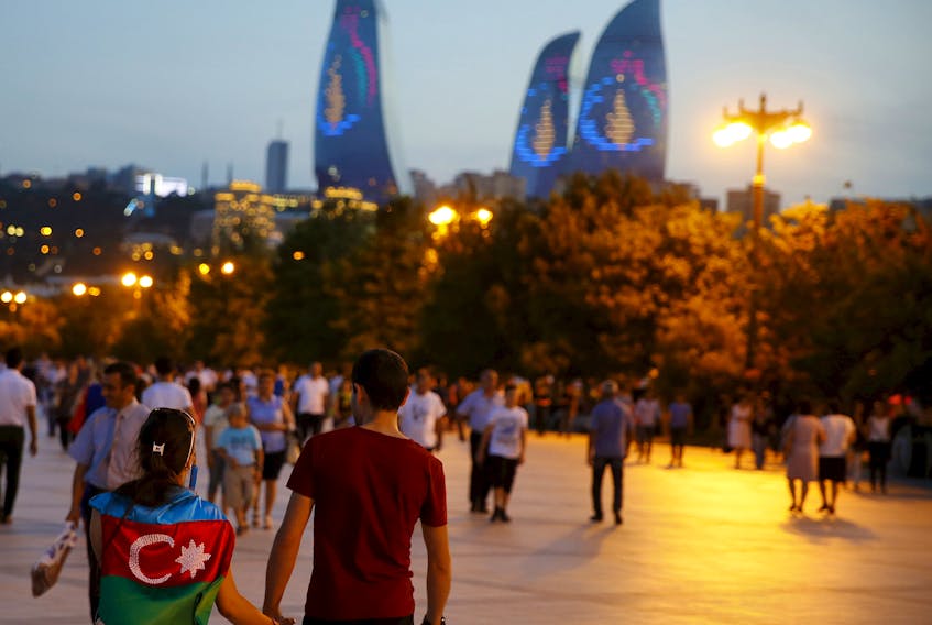 A girl, draped in Azerbaijan's national flag, walks with a boy on a street in downtown Baku, Azerbaijan June 18, 2015. 