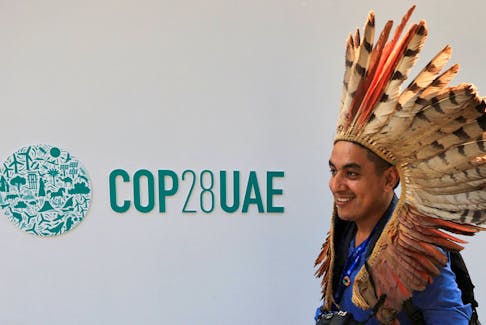A delegate walks past a logo of the COP28 climate summit in Dubai, United Arab Emirates, December10, 2023.