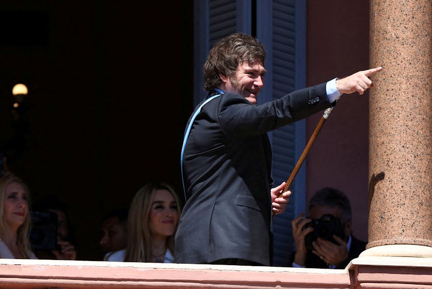 Argentina's President Javier Milei gestures to supporters from the Casa Rosada balcony, as his sister Karina Milei and his partner Fatima Florez look on, after his swearing-in ceremony, in Buenos Aires, Argentina December 10, 2023.