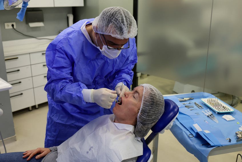 Turkish dentist Ertan Etemoglu treats his patient Marion Parks, a 55-year-old British woman from a village near Ipswich, Suffolk, during a dental implant operation at Tower Dental Clinic in Istanbul, Turkey December 4, 2023.